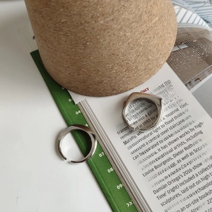 Minimalist silver open rings with geometric square and sleek curved designs shown on a magazine