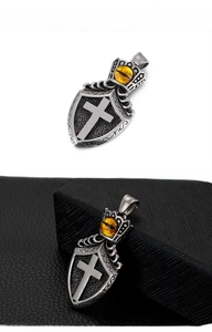 Detailed macro view of vintage shield cross pendant with crown and yellow gemstone inlay