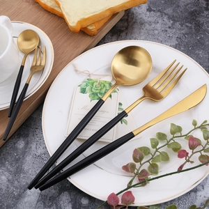 Modern black and gold 304 stainless steel cutlery set with brushed finish on white plate