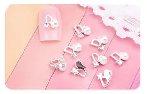 Détail d'un bijou d'ongle en alliage en forme de D avec perles blanches et strass