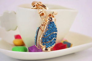 Detail of a golden golf bag keychain with sparkling blue rhinestones and metal ring
