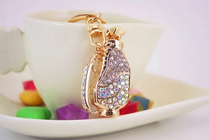 Close-up of a sparkling gold golf bag keychain with colorful rhinestones on a white background