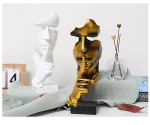 Detailed close-up of golden and white Silence is Gold sculptures on a modern shelf
