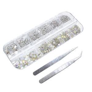 Detailed view of 12-grid nail art rhinestones with tweezers on white background