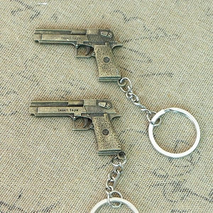 Macro shot of vintage brass desert eagle pistol keychain on a rustic burlap background