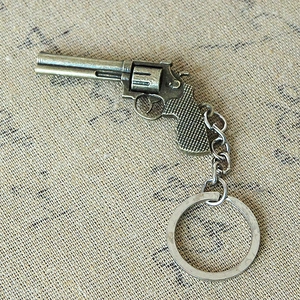 Detailed close-up of a vintage metal revolver pistol keychain on textured fabric surface