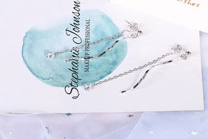 Detail of silver S-shaped wave tassel earrings with sparkling zircon on a stylish background