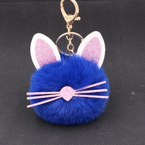 Detail of blue plush kitten keychain with pink glitter ears and gold ring on black base