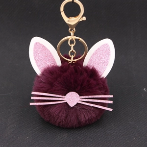 Close-up of deep purple plush ball keychain with glitter cat ears and gold clasp