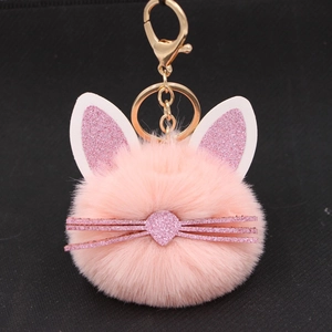Close-up of pink plush cat keychain with gold keyring on black background