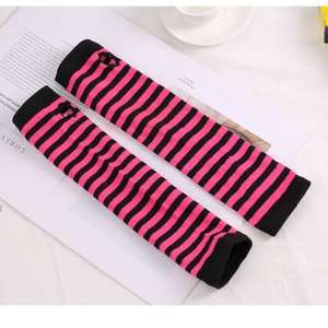 Detail of pink and black striped knitted arm warmers with thumb holes on a magazine