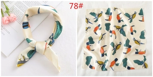 Detail of silk satin square scarf featuring colorful toucan bird and tropical leaf print