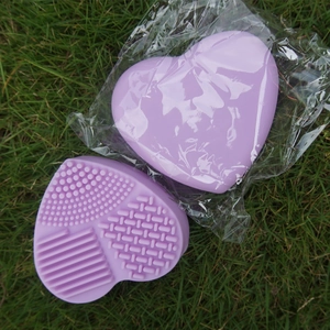 Macro shot of purple heart-shaped silicone makeup brush cleaning mat with varied textures