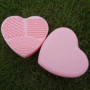 Pink heart-shaped silicone makeup brush cleaning pad with various textured surfaces for washing