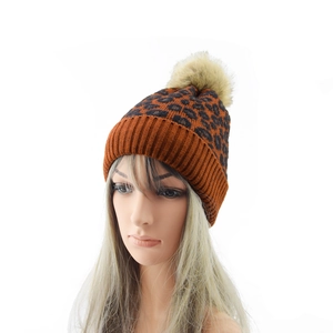 Detailed close-up of leopard print knit beanie with a fluffy pompom and ribbed cuff