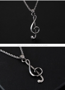 Detail view of silver treble clef music pendant with twist chain in titanium steel
