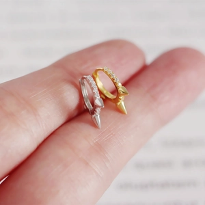 Detail view of gold and silver S925 sterling silver hoop earrings with spikes and crystals