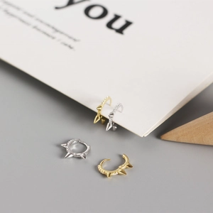 Detailed view of punk style silver and gold ear cuffs with spikes and clear crystals