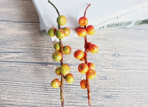 Detailed view of artificial orange berry branches with realistic wood texture on rustic desk