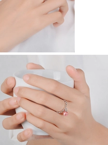 Close-up of a silver heart ring with a pink crystal ball pendant on a hand