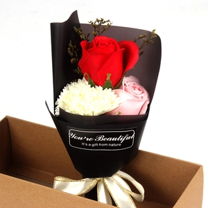 Soap flower bouquet detail with red rose and carnation in a brown cardboard gift box
