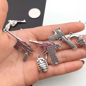 Antik-silberne Pistolen- und Granaten-Anhänger für DIY-Schmuck auf einer Handfläche