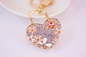Detail of heart keychain with purple rhinestones, enamel flowers and a large peach gem