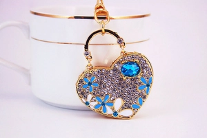 Detail of heart keychain with blue flowers and crystal rhinestones against a white cup