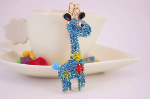 Close-up of a blue crystal giraffe keychain with colorful rhinestones on a metal base