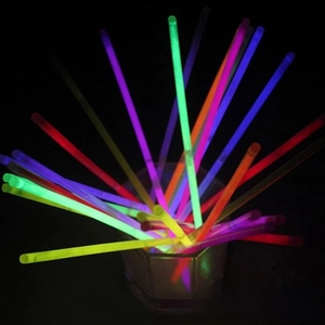 Close-up of vibrant multi-color glow sticks glowing in a glass jar against a dark background