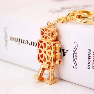 Robot-shaped metal keychain in gold with cutout patterns and rhinestone eye accents