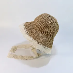 Détail du chapeau de paille beige avec bordure en dentelle blanche et rubans longs