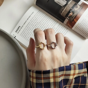 Detail of minimalist gold and silver interlocking rings styled with vintage plaid shirt
