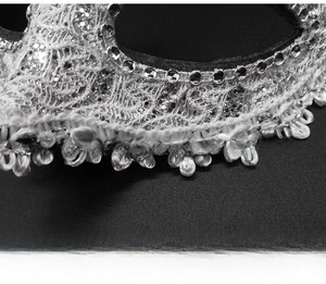 Detail of white lace masquerade mask with sparkling rhinestones and silver glitter finish