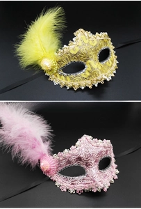 Detailed view of yellow and pink lace masquerade masks with decorative feathers and sequins