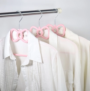 Pink butterfly-shaped plastic hangers with non-slip design holding white shirts on a rod