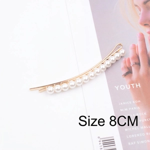 Detail view of 8cm gold pearl hair clip with 14 white faux pearls on magazine background