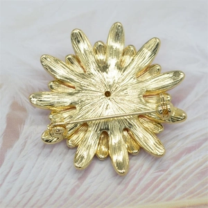 Close-up of the metal pin fastener on the back of a golden floral enamel brooch