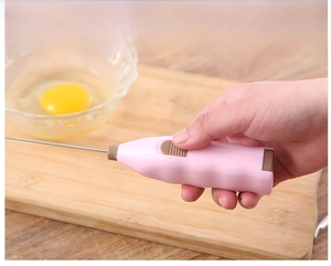 Close-up of pink handheld milk frother with stainless steel whisk and slide switch