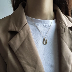 Close-up of golden U-shaped lava texture pendant on model wearing a blazer