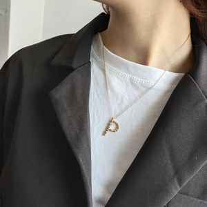 Detailed view of a gold-plated letter P pendant necklace worn on a textured chain