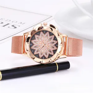 Détail d'une montre rose gold avec cadran lotus serti à côté d'accessoires de bureau