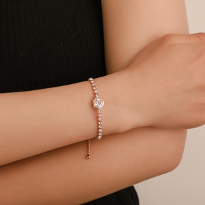 Detail of rose gold heart-shaped tennis bracelet with adjustable pull-chain on wrist