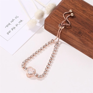 Rose gold adjustable heart bracelet with clear cubic zirconia on a minimalist wood base