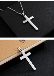 Macro shot of silver cross pendant with polished stainless steel surface and twisted chain
