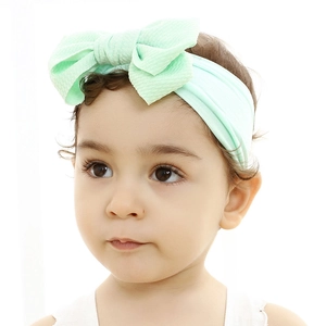 Infant wearing a soft mint green nylon headband with a large textured knot bow accessory