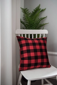 Close-up of a classic red and black buffalo plaid cushion on a minimalist white chair
