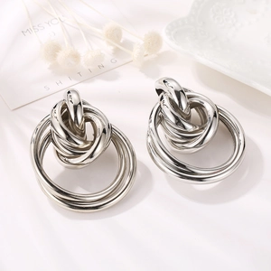 Macro shot of silver multi-layer twisted knot hoop earrings on a decorative plate