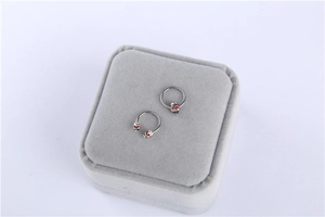Detail view of surgical steel nipple rings with skull design and red rhinestone eyes