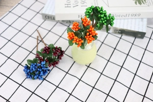 Close-up of colorful artificial berry stems in blue, burgundy and orange for DIY home decor